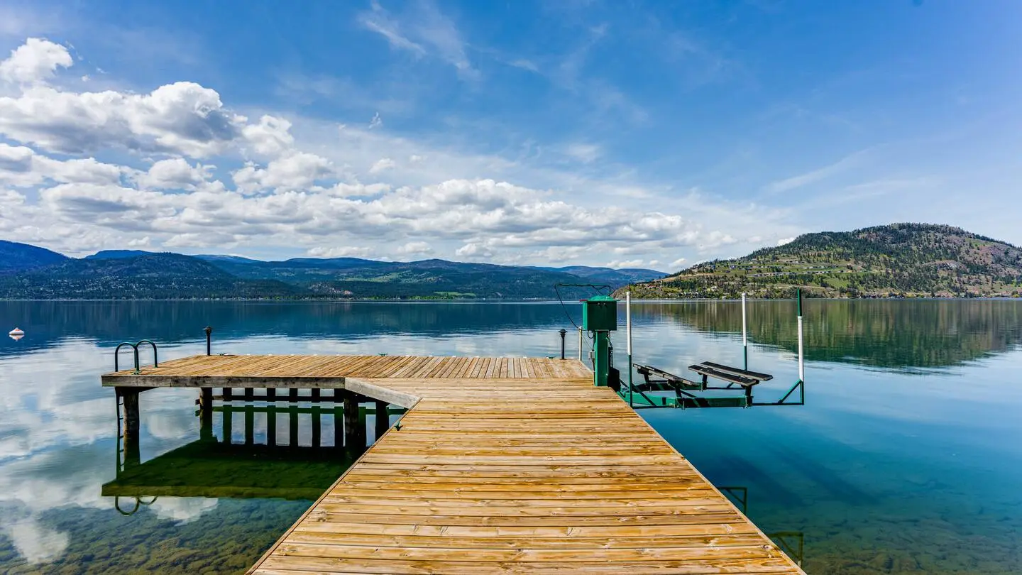 Private wooden dock on Okanagan Lake under a blue sky