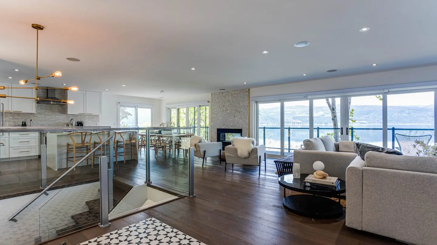 Open-plan living room and kitchen with glass railings and lake views