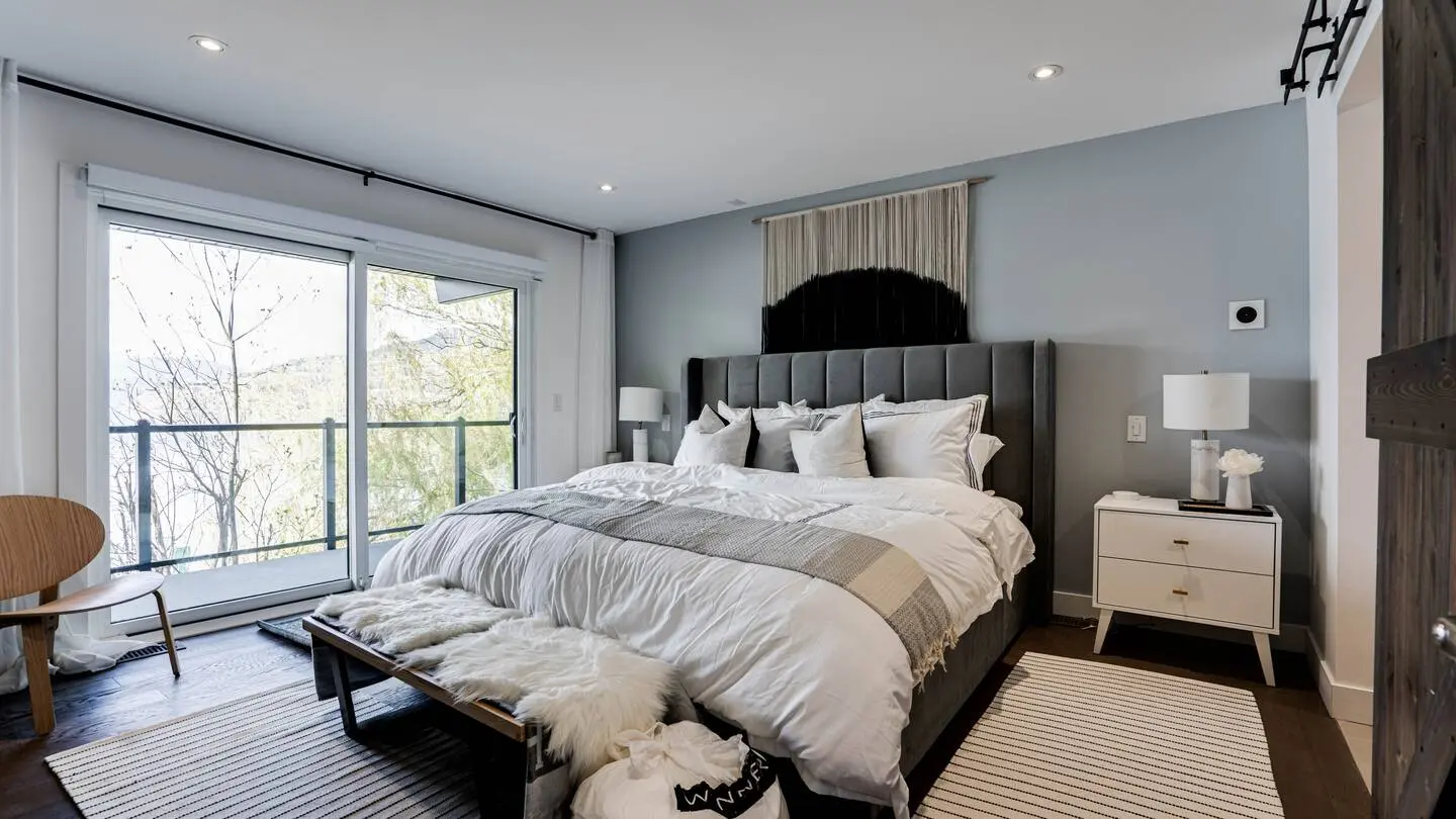 Bedroom with upholstered bed and sliding doors to a lake-view balcony